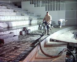 One worker puts down concrete using a hose while the other worker smooths the concrete. - , Utah